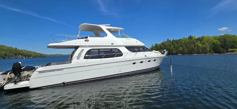 Slide: The Image of 2005 Carver 560 Voyager yacht on a serene lake under a clear blue sky. - 1