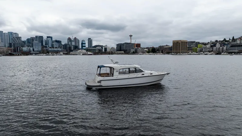 Slide: The Image of Nimbus 365 Coupe boat on water with city skyline in background, overcast sky. - 1