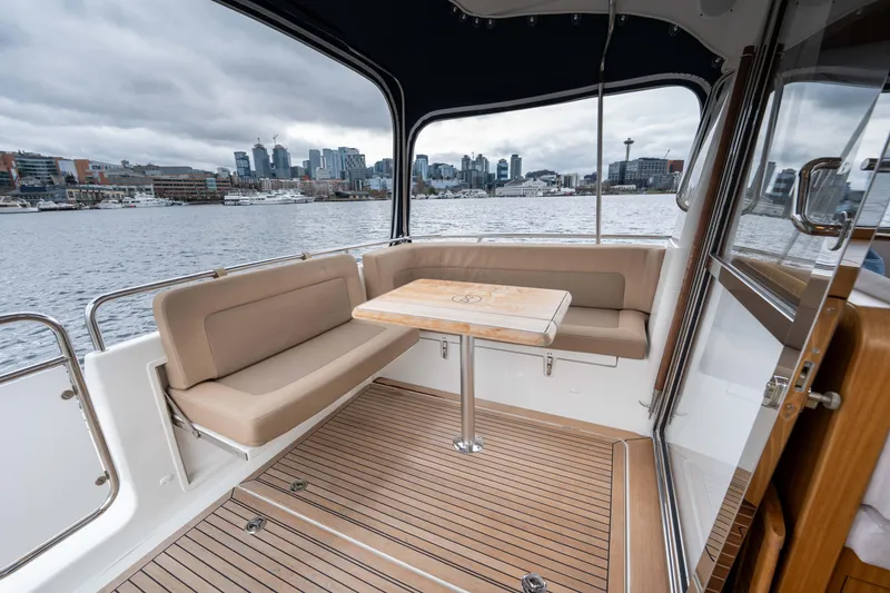 Slide: The Image of 2017 Nimbus 365 Coupe boat interior with city skyline view, featuring a cozy seating area. - 15