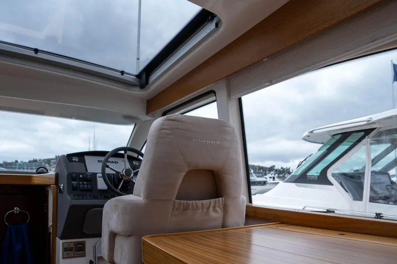 Slide: The Image of Interior of 2017 Nimbus 365 Coupe boat with steering wheel and wooden table. - 23