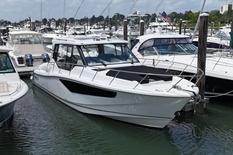Slide: The Image of 2021 Boston Whaler 405 Conquest docked in a marina, surrounded by other boats. - 16