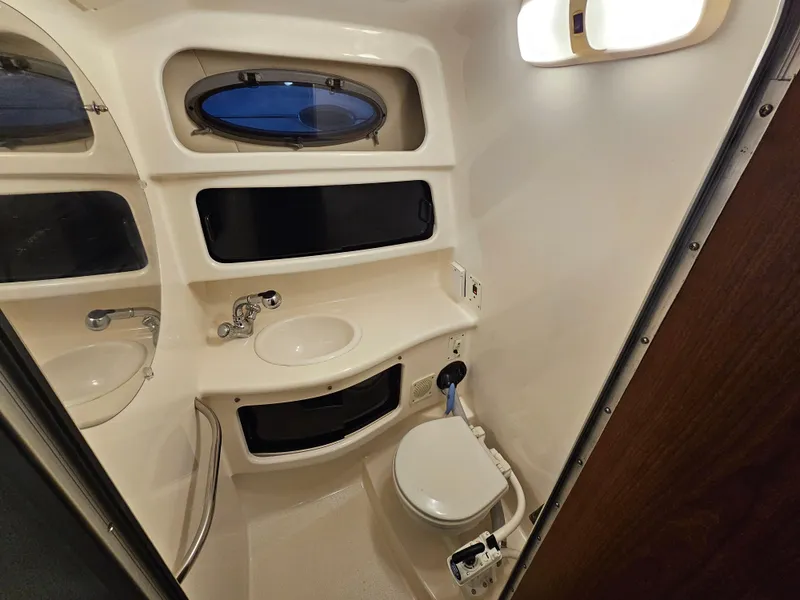 Slide: The Image of 2003 Chaparral 260 Signature Cruiser bathroom with sink, toilet, and porthole window. - 8