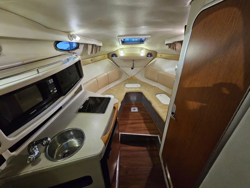 Slide: The Image of 2003 Chaparral 260 Signature Cruiser interior with kitchenette, seating, and wood accents. - 4