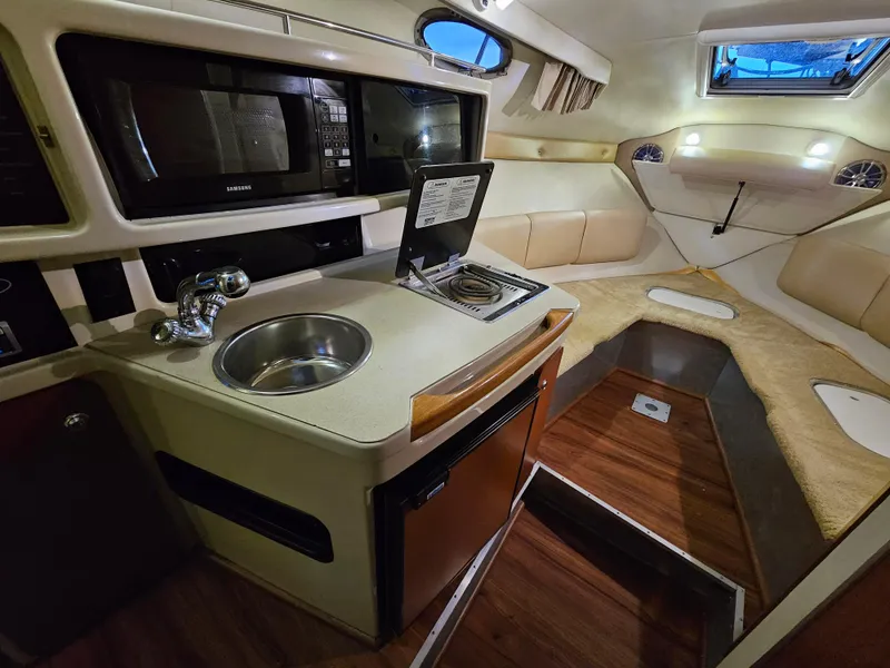 Slide: The Image of 2003 Chaparral 260 Signature Cruiser interior with kitchenette, sink, and cozy seating area. - 6