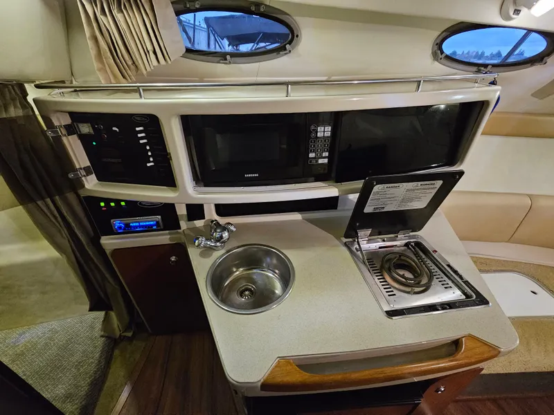 Slide: The Image of 2003 Chaparral 260 Signature Cruiser interior kitchen with sink, stove, and microwave. - 7