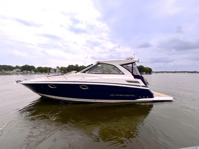 Slide: The Image of 2014 Regal 35 Sport Coupe boat on calm water under cloudy sky. - 1