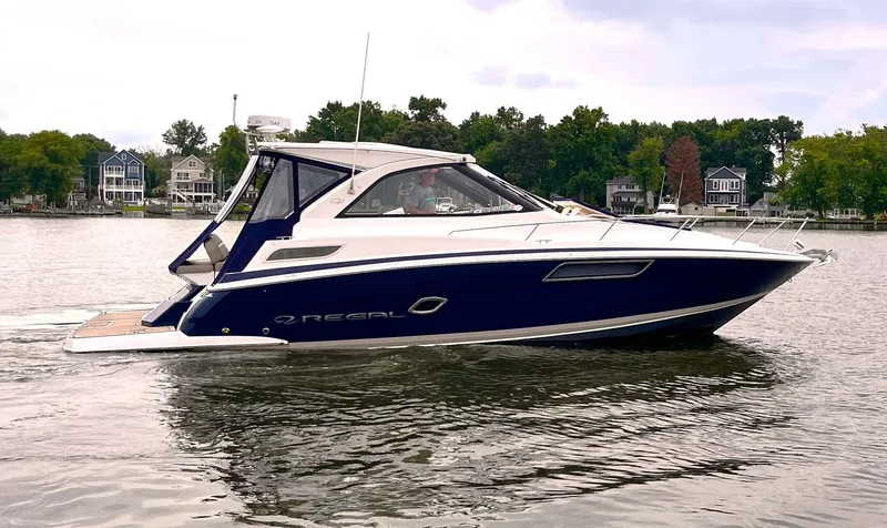 Slide: The Image of 2014 Regal 35 Sport Coupe boat cruising on a calm lake with scenic background. - 2