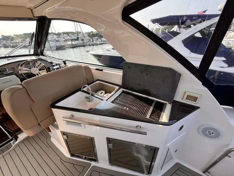 Slide: The Image of 2014 Regal 35 Sport Coupe interior with kitchenette and seating, docked at marina. - 23