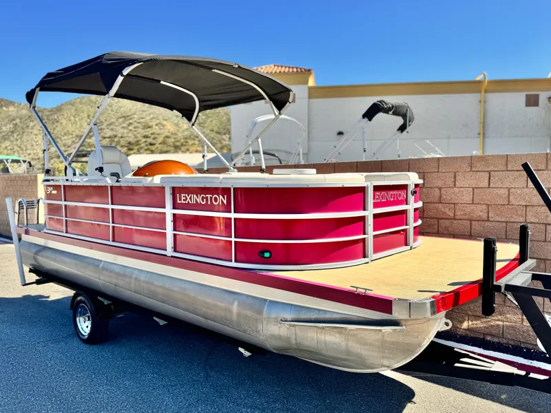 Slide: The Image of 2023 Lexington 321 CRUISE pontoon boat with red exterior and black canopy. - 1