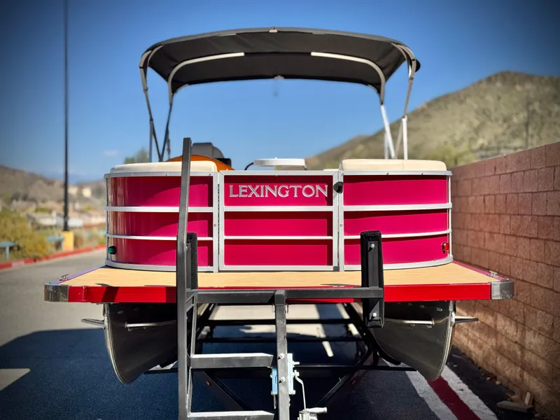 Slide: The Image of 2023 Lexington 321 CRUISE pontoon boat with red exterior and canopy, parked on a sunny day. - 2