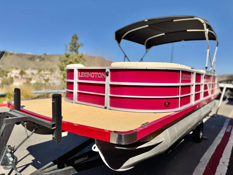 Slide: The Image of 2023 Lexington 321 CRUISE pontoon boat with red exterior and canopy, parked on trailer. - 4
