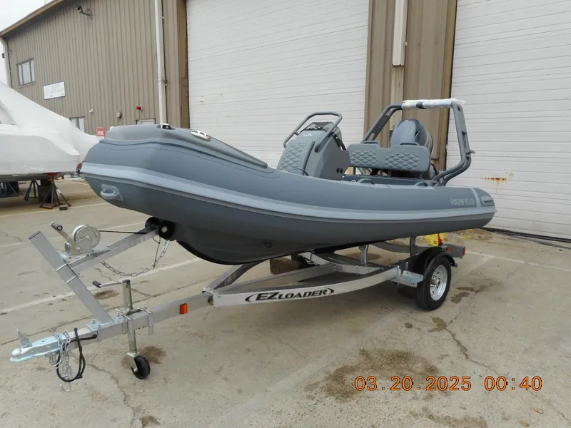 The Image of 2025 Highfield Sport 390 boat on EZ Loader trailer, parked outside a warehouse. - 0