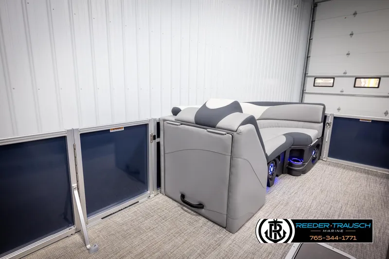 Slide: The Image of 2025 Avalon LSZ Entertainer pontoon interior with gray seating and blue accents in a showroom. - 20