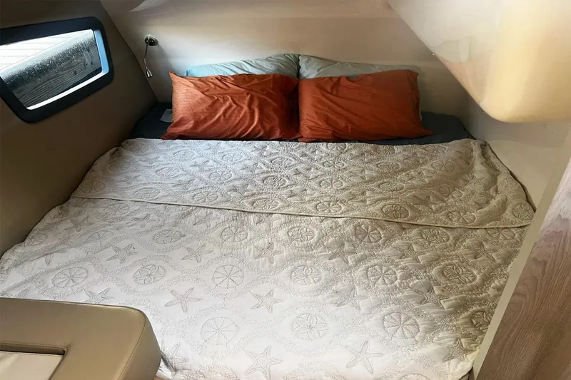 Slide: The Image of Cozy bed in 2024 Hanover 375 cabin with starfish-patterned quilt and orange pillows. - 16