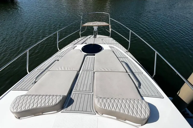Slide: The Image of 2024 Hanover 375 boat deck with cushioned sunbeds on calm water. - 3