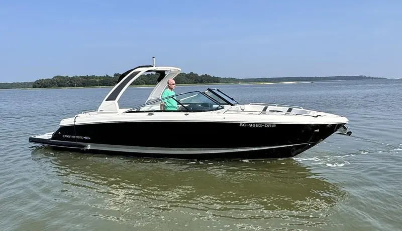 Slide: The Image of 2021 Chaparral 307 SSX boat cruising on a calm lake under a clear blue sky. - 1