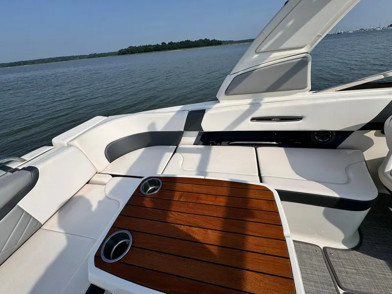 Slide: The Image of 2021 Chaparral 307 SSX boat interior with wooden table and cushioned seating. - 12