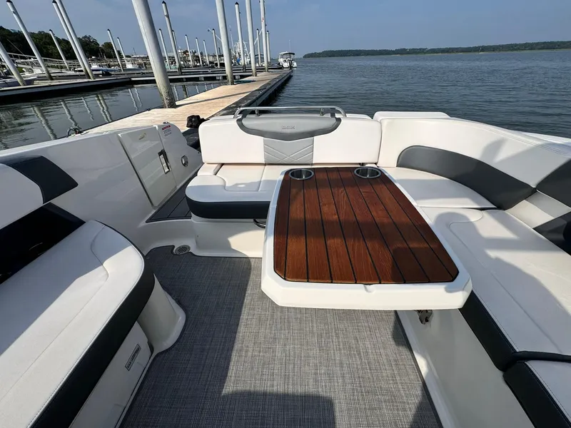 Slide: The Image of 2021 Chaparral 307 SSX boat interior with seating and wooden table by the dock. - 13