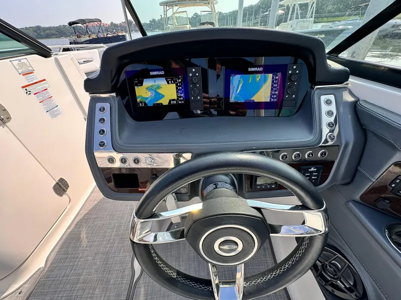 Slide: The Image of 2021 Chaparral 307 SSX boat dashboard with dual Simrad displays and steering wheel. - 18