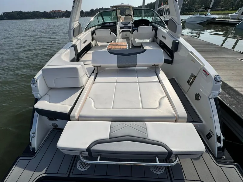 Slide: The Image of 2021 Chaparral 307 SSX boat with spacious seating and sunbed, docked by a serene lake. - 22