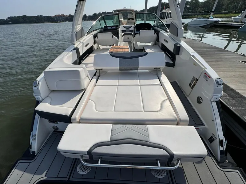 Slide: The Image of 2021 Chaparral 307 SSX boat with spacious seating and sunbed, docked by the water. - 23