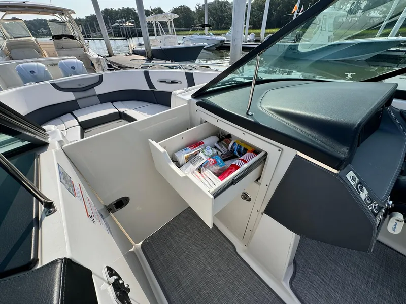 Slide: The Image of 2021 Chaparral 307 SSX boat interior with open storage compartment, docked at marina. - 39