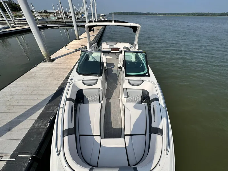 Slide: The Image of 2021 Chaparral 307 SSX boat docked on calm water, showcasing sleek design and spacious seating. - 4