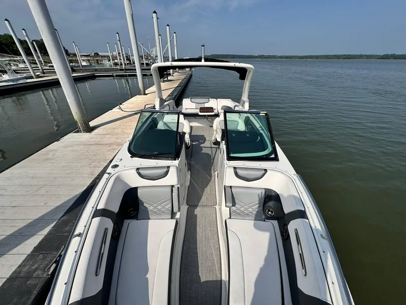 Slide: The Image of 2021 Chaparral 307 SSX boat docked on a calm lake under a clear blue sky. - 5