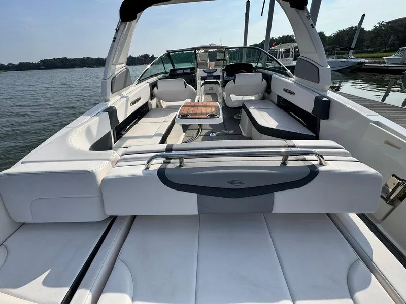 Slide: The Image of 2021 Chaparral 307 SSX boat with spacious seating and sleek design on a calm lake. - 9
