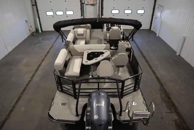 Slide: The Image of 2021 SunChaser 23 SBX Eclipse Tri-Toon boat in indoor storage, showcasing seating and motor. - 10