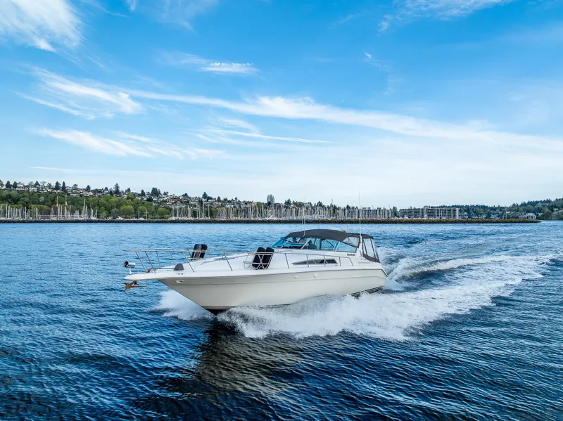 Slide: The Image of 1991 Sea Ray 420 Sundancer cruising on a scenic lake under a clear blue sky. - 2
