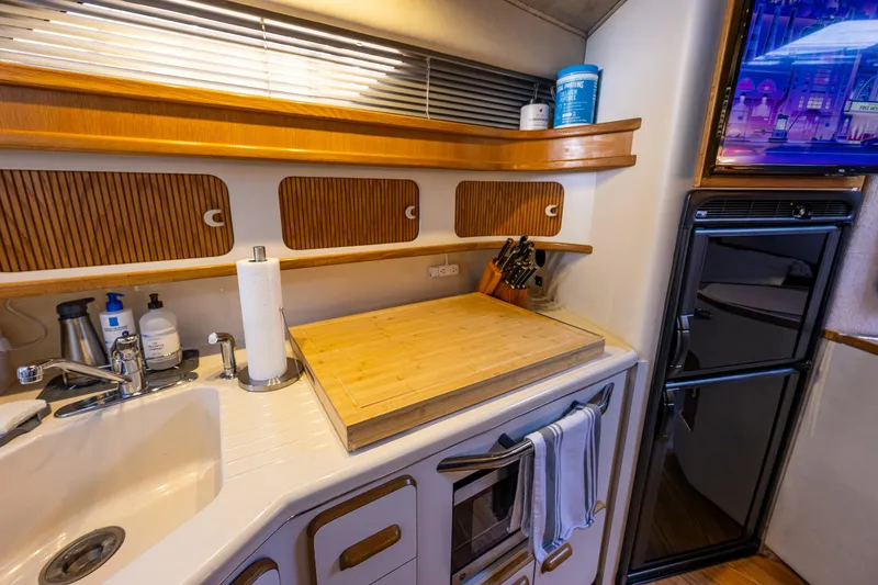 Slide: The Image of 1991 Sea Ray 420 Sundancer kitchen with sink, cutting board, and storage cabinets. - 25