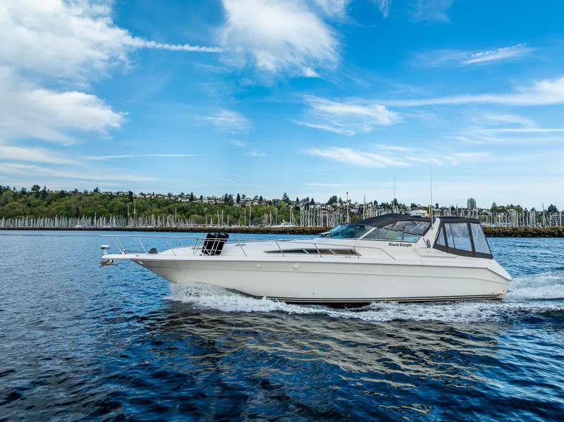 Slide: The Image of 1991 Sea Ray 420 Sundancer cruising on a scenic lake under a clear blue sky. - 3