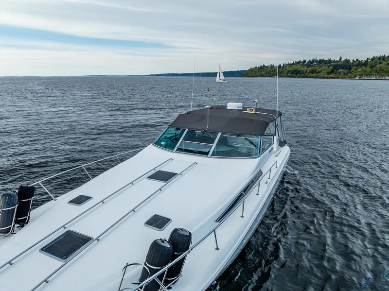 Slide: The Image of Sea Ray 420 Sundancer 1991 cruising on open water with distant sailboat and shoreline. - 7
