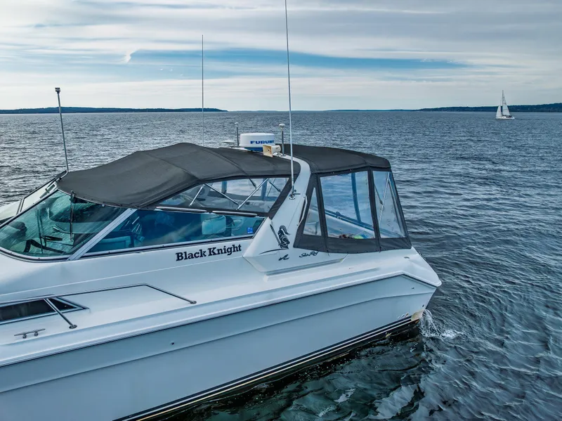 Slide: The Image of Sea Ray 420 Sundancer 1991 boat on open water with sailboat in background. - 8