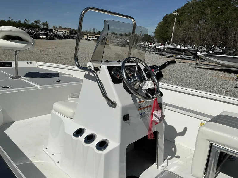 Slide: The Image of 2025 G3 Bay 20 boat interior with steering console and seating, parked outdoors. - 11