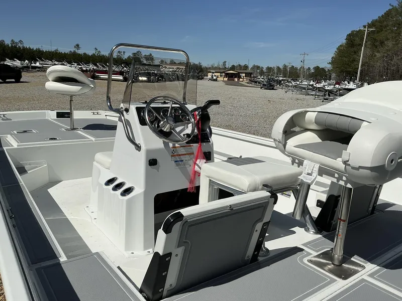 Slide: The Image of 2025 G3 Bay 20 boat interior with steering console and seating, parked outdoors. - 14
