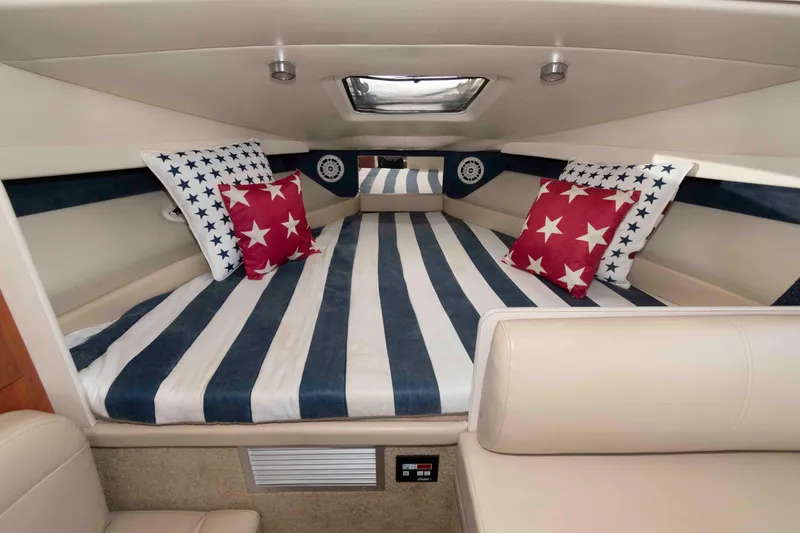 Slide: The Image of Interior of 2008 Bayliner 285 boat with star-patterned bedding and striped cushions. - 5