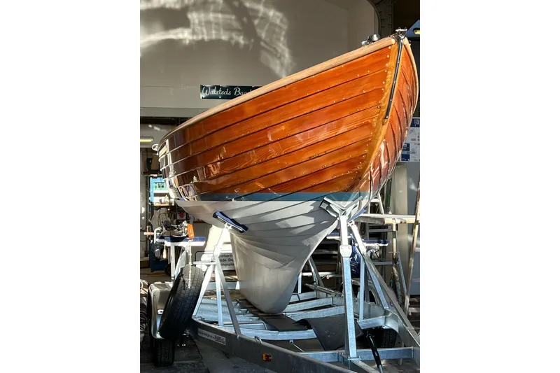Slide: The Image of 1979 Nordic Folkboat with polished wooden hull on a trailer in a workshop. - 2
