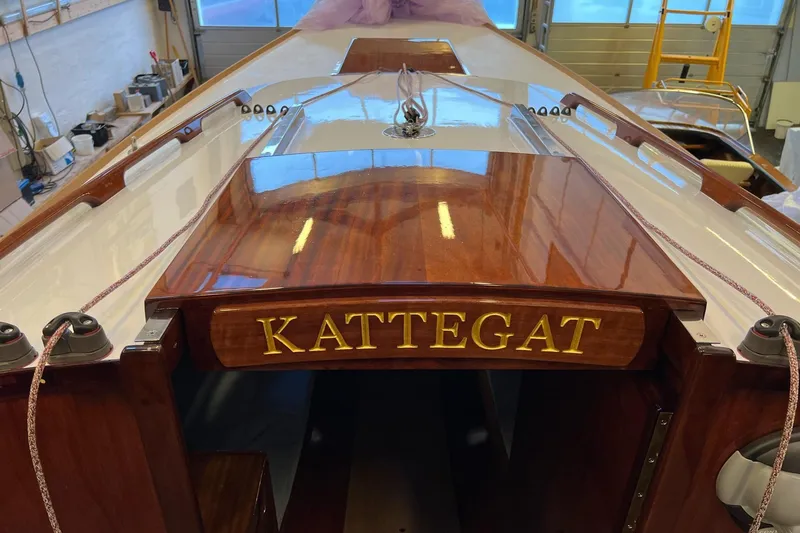 Slide: The Image of 1979 Nordic Folkboat "Kattegat" with polished wood finish in a workshop setting. - 20