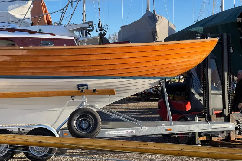 Slide: The Image of 1979 Nordic Folkboat on trailer, showcasing polished wooden hull in a boatyard. - 7