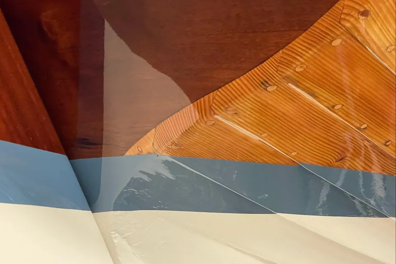 Slide: The Image of Close-up of a 1979 Nordic Folkboat's polished wooden hull with blue and white paint. - 8