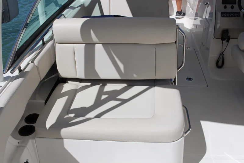 Slide: The Image of 2014 Boston Whaler 270 Vantage boat interior with cushioned seating and cup holders. - 11