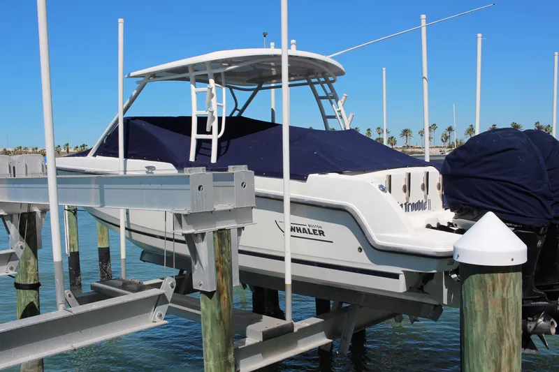 Slide: The Image of 2014 Boston Whaler 270 Vantage boat docked on a lift, covered, with clear blue sky. - 18
