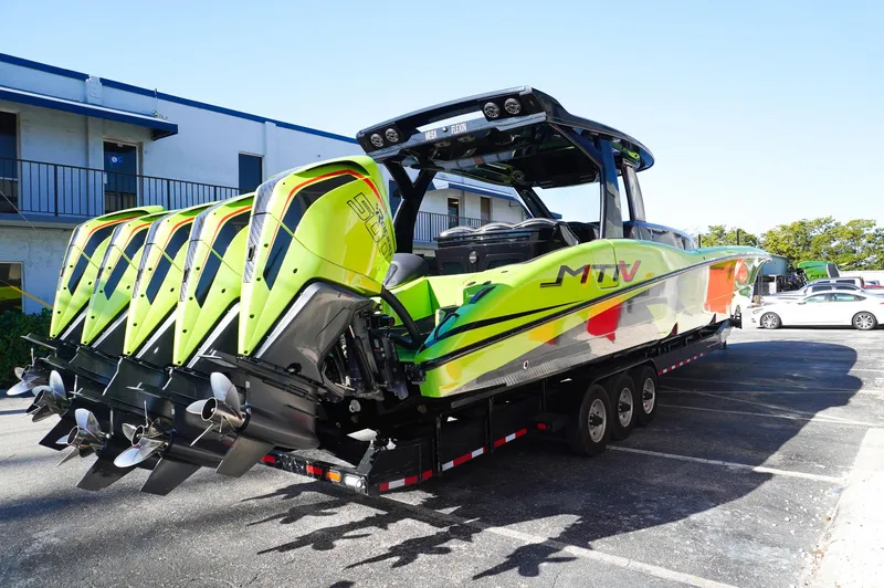 Slide: The Image of 2022 MTI 50V Center Console boat with vibrant design and multiple engines on a trailer. - 6