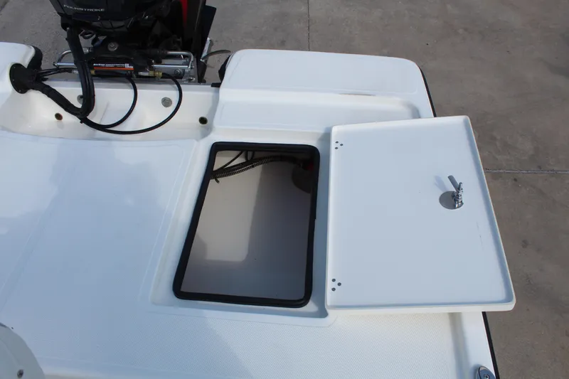 Slide: The Image of 2025 Mako 18 LTS boat storage compartment with open hatch and visible engine components. - 18