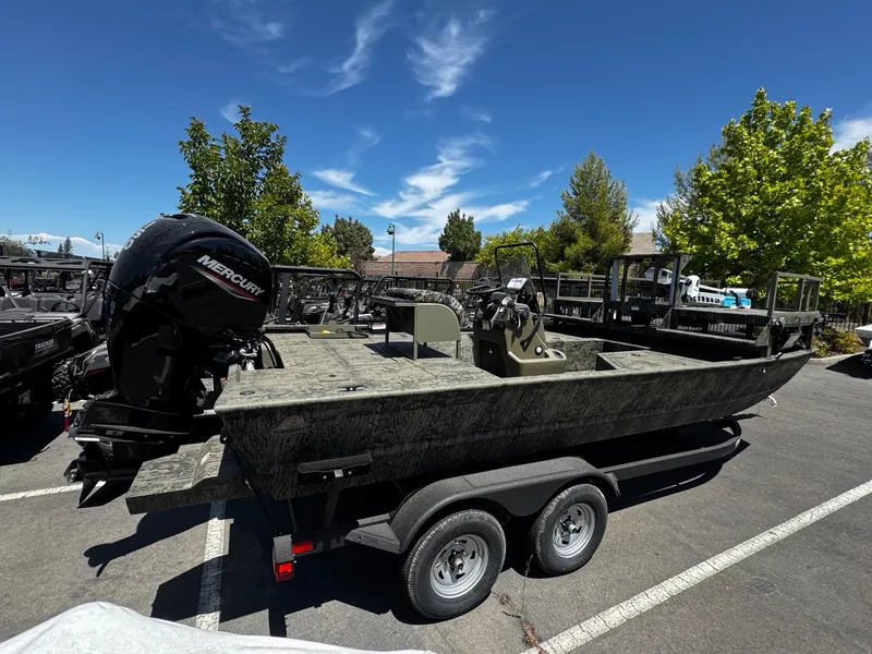 Slide: The Image of 2025 Tracker Grizzly 2072 CC Sportsman boat on trailer, parked outdoors under clear sky. - 2