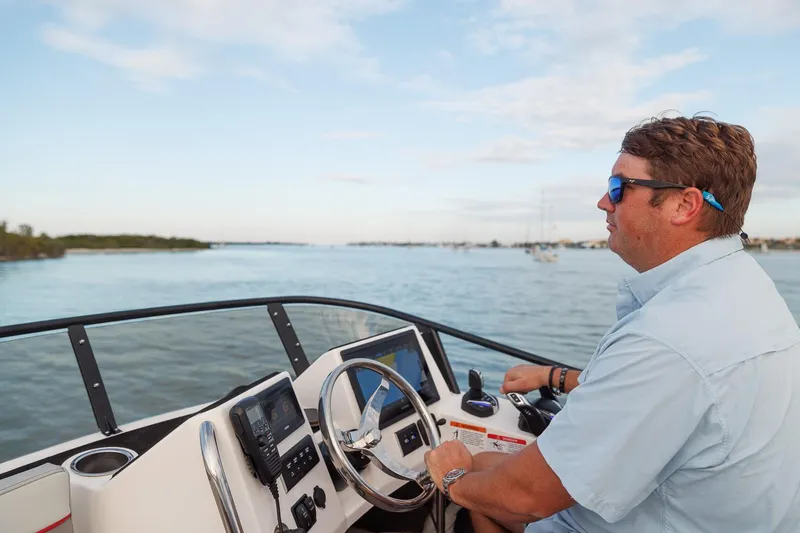 Slide: The Image of Man steering 2026 Solara S-310 Sport Bridge boat on calm waters. - 10