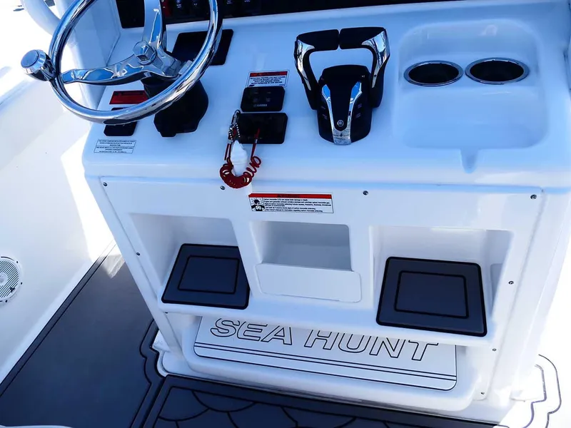Slide: The Image of 2021 Sea Hunt Gamefish 27 helm with controls, steering wheel, and storage compartments. - 15