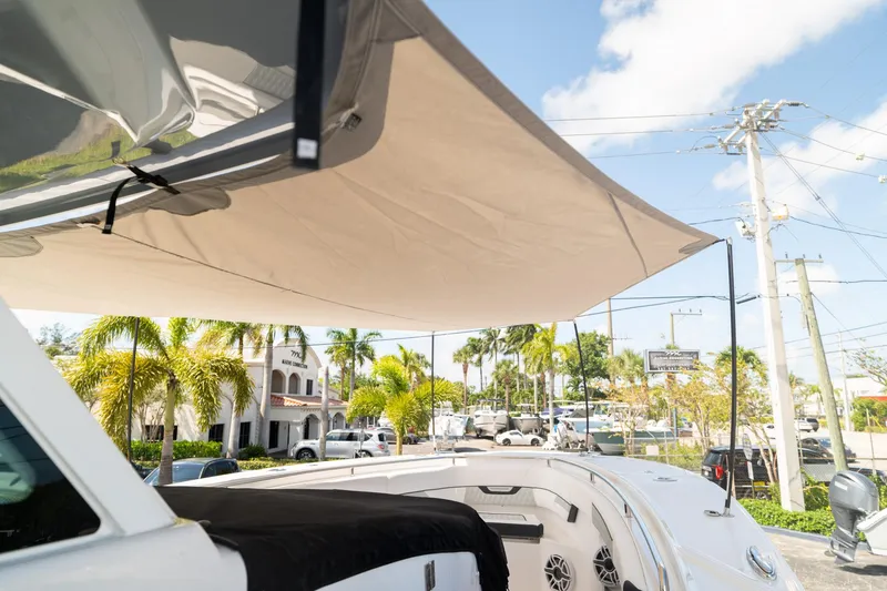 Slide: The Image of 2024 Blackfin 400 CC boat with sunshade, parked near palm trees and buildings. - 16
